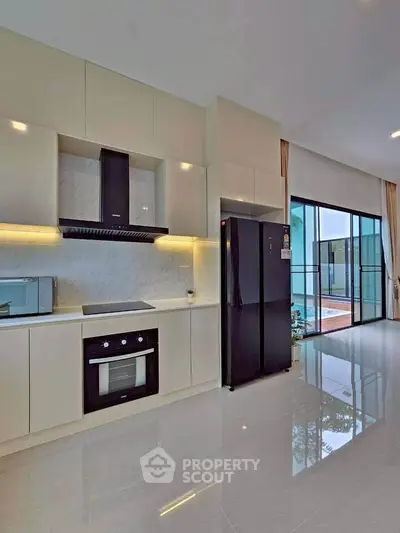 Modern kitchen with sleek cabinetry, built-in oven, and large refrigerator in a spacious open layout.