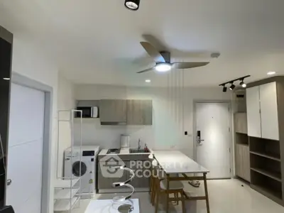 Modern kitchen with sleek cabinetry, dining area, and ceiling fan in a contemporary apartment.