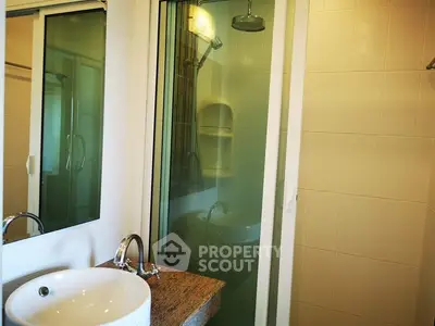 Compact bathroom with modern shower and sink in cozy apartment.
