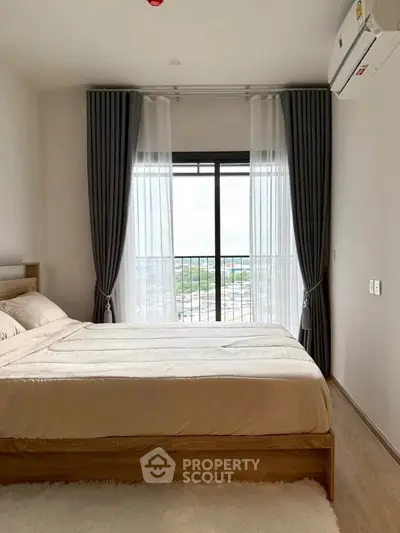 Modern bedroom with large window and city view, featuring elegant curtains and cozy bedding.