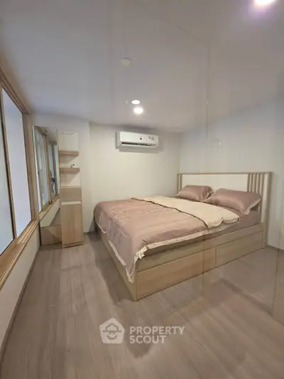Cozy bedroom with modern design and ample natural light, featuring a comfortable bed and sleek wooden flooring.