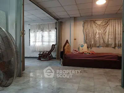Spacious bedroom with marble flooring and natural light, featuring a cozy bed and rocking chair.