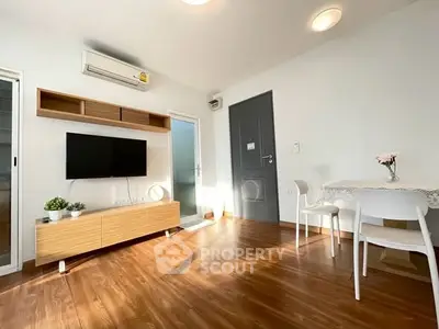 Bright modern living room with wooden flooring, wall-mounted TV, and dining area.