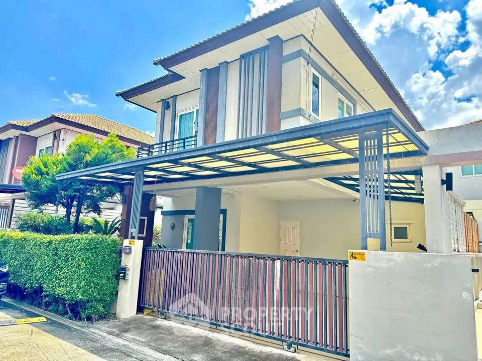 Modern two-story house with a spacious carport and lush greenery, ideal for family living.