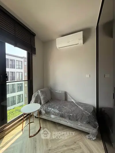 Modern apartment corner with cozy sofa, air conditioning, and large window view.
