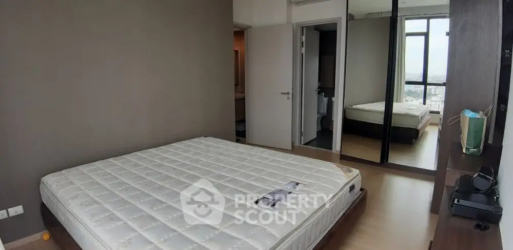 Spacious bedroom with large mirror and city view, ideal for modern living.