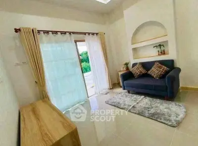 Cozy living room with stylish sofa and natural light from large window, perfect for relaxation.