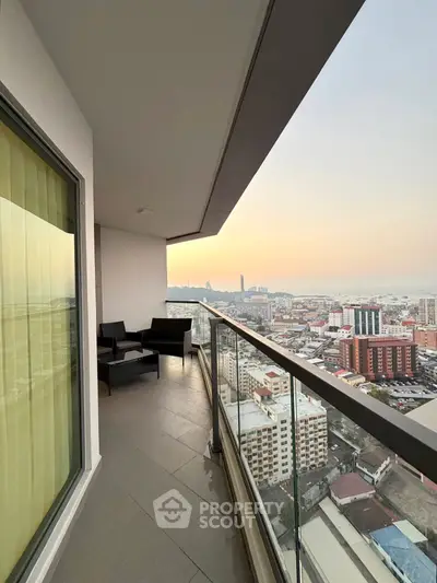 Stunning high-rise balcony with panoramic city and ocean views at sunset.