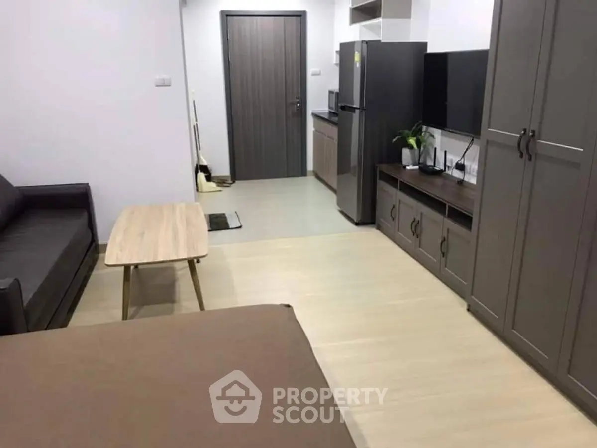 Modern studio apartment with sleek furniture and compact kitchen area.