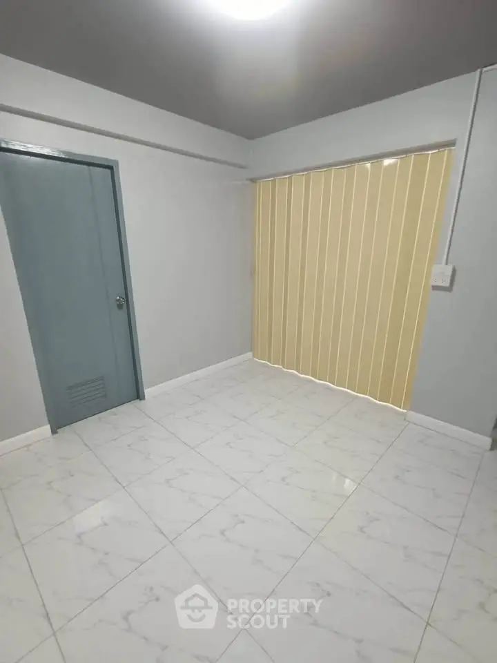 Spacious empty room with tiled floor and vertical blinds, ideal for customization.