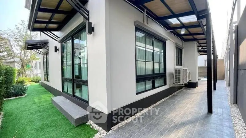 Modern exterior view of a stylish home with lush green lawn and sleek design.