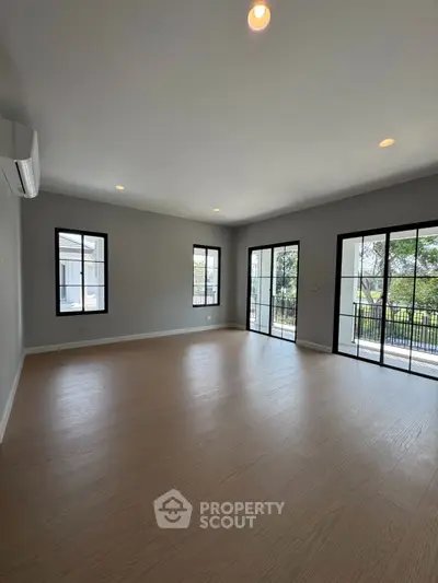 Spacious modern living room with large windows and balcony access, perfect for natural light lovers.