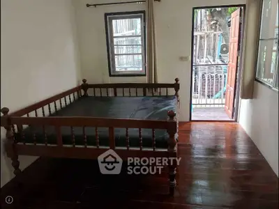Cozy bedroom with wooden flooring and open door to balcony