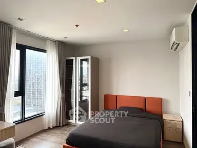 Modern bedroom with city view, featuring sleek furniture and large windows for natural light.
