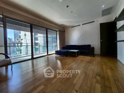 Spacious living room with hardwood floors and large windows in modern apartment.