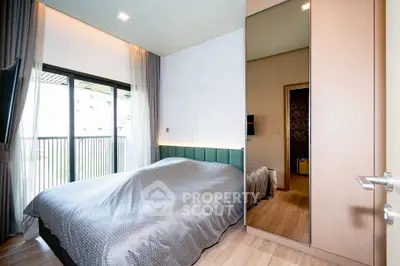 Modern bedroom with large window and balcony access, featuring stylish decor and ample natural light.