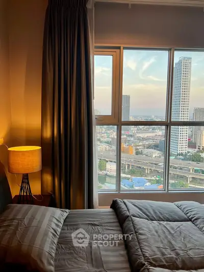Cozy bedroom with stunning city view from large window, featuring elegant decor and warm lighting.