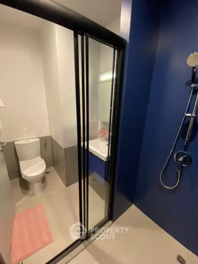 Modern bathroom with sleek shower and toilet, featuring blue accent wall and contemporary fixtures.