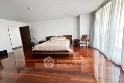 Spacious bedroom with polished wooden floors and large windows