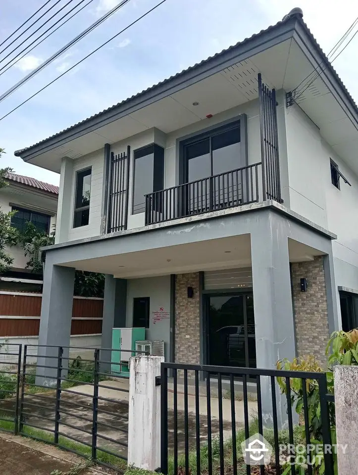 Modern two-story house with sleek design and spacious balcony in a suburban neighborhood.