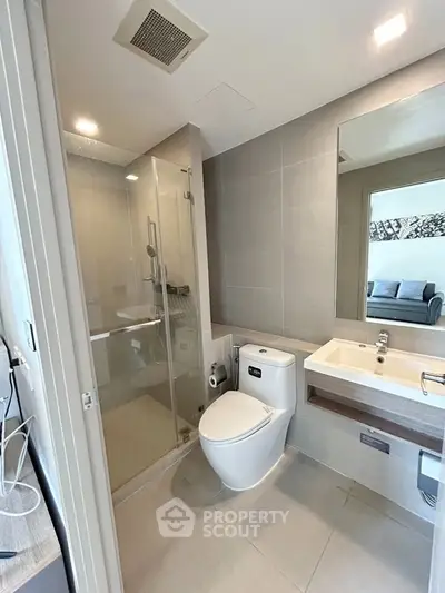 Modern bathroom with glass shower and sleek fixtures in contemporary apartment.
