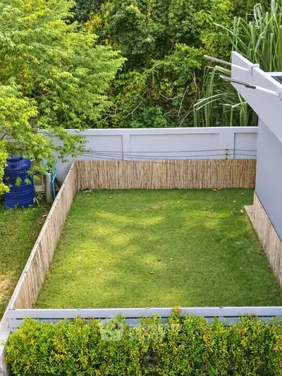 Charming backyard with lush green lawn and privacy fence, perfect for outdoor relaxation.
