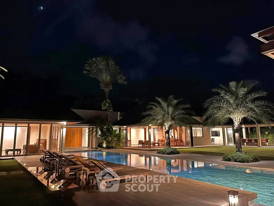 Luxurious villa with stunning pool and lush garden at night, perfect for serene living.