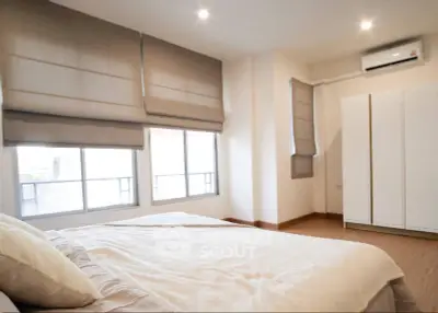 Spacious bedroom with large windows and modern decor in a stylish apartment.