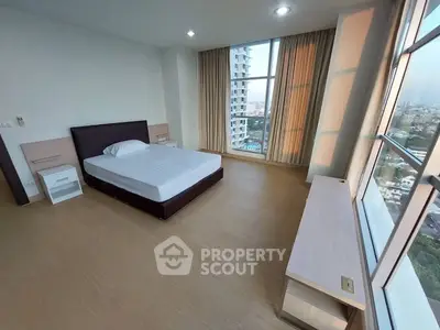 Spacious bedroom with large windows offering stunning city views in a modern high-rise apartment.