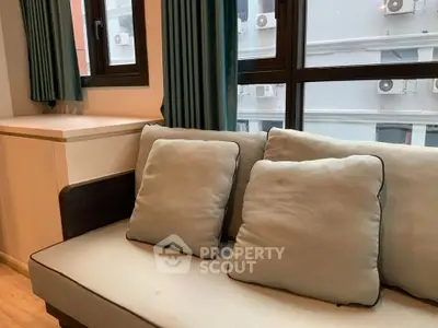 Cozy living room with modern sofa and large windows offering city views.