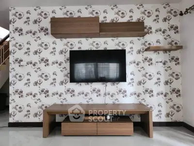 Modern living room with floral wallpaper and mounted TV, featuring sleek wooden furniture.