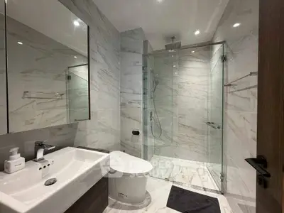 Luxurious modern bathroom with marble tiles and glass shower enclosure