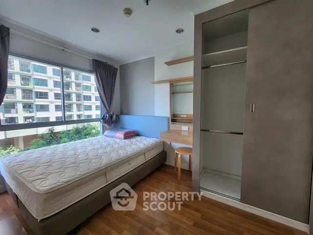 Modern bedroom with large window and built-in wardrobe in urban apartment