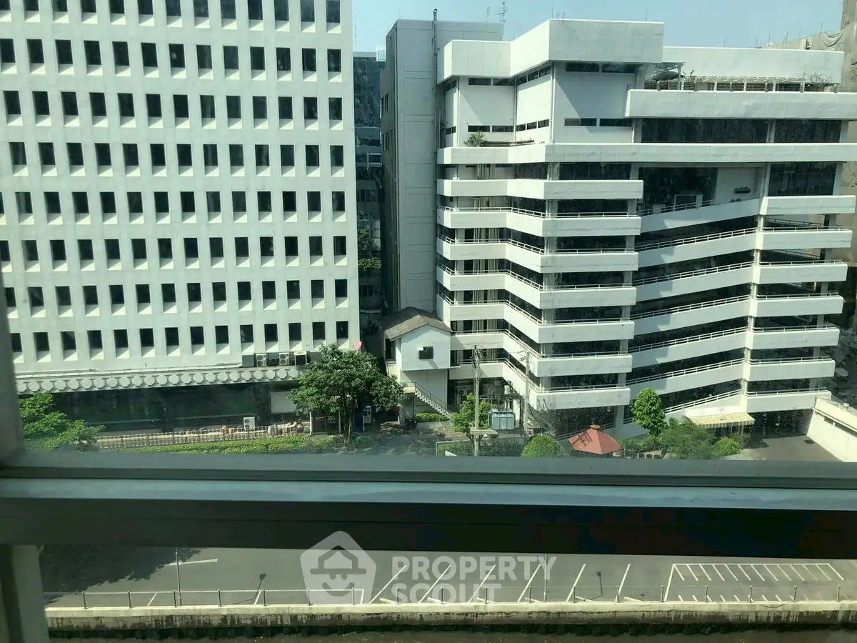 Urban view from window showcasing modern office buildings and parking area.