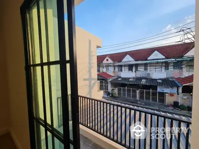 Charming balcony view of residential neighborhood with red-tiled roofs and clear blue sky.