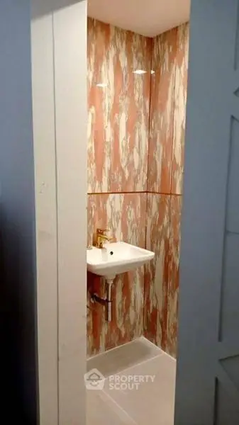 Compact bathroom with stylish marble-patterned walls and modern sink.
