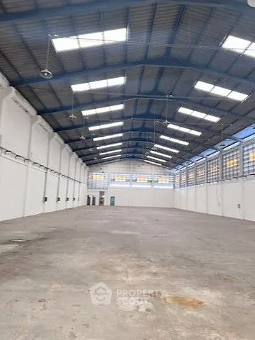 Spacious industrial warehouse with high ceilings and ample natural light.