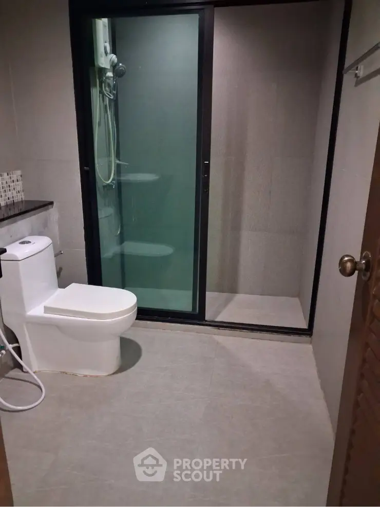 Modern bathroom with glass shower enclosure and sleek toilet design.