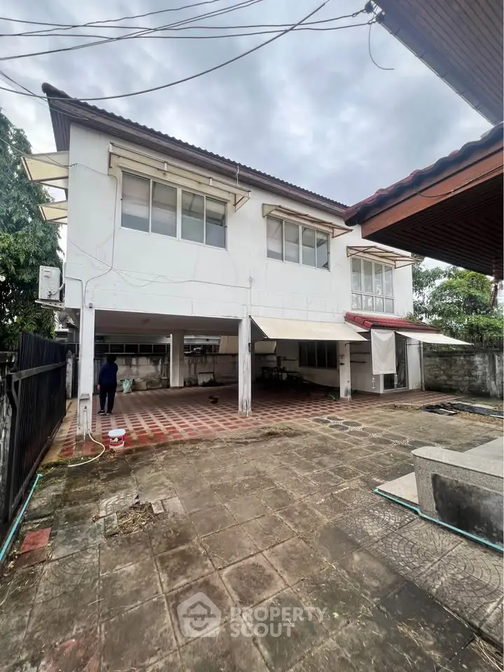 Spacious two-story house with large outdoor area and tiled patio, perfect for family gatherings.