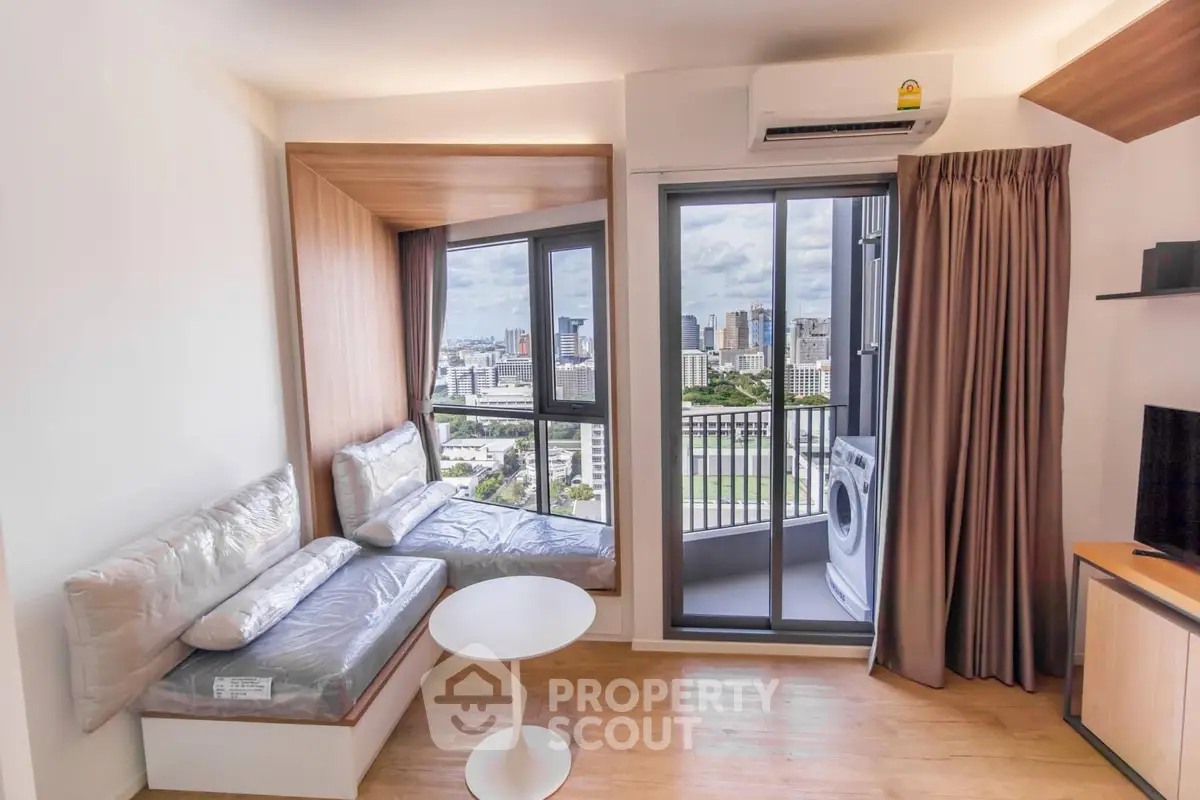 Modern living room with city view and balcony access, featuring cozy seating and air conditioning.