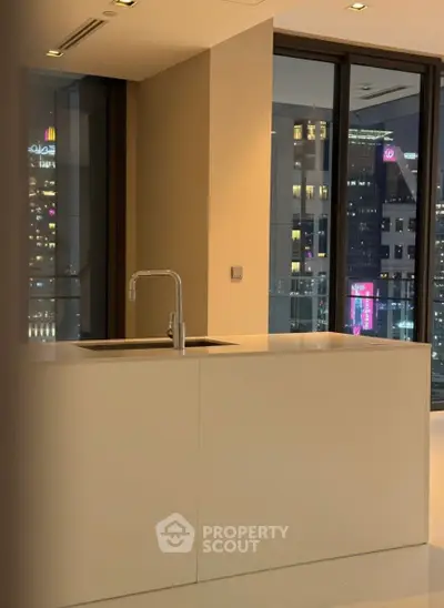 Modern kitchen with sleek design and city view from large windows.