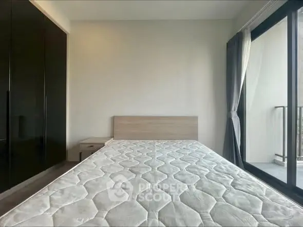 Modern bedroom with large window and sleek wardrobe, offering ample natural light and storage.