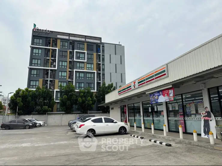 Modern condo building next to a convenience store with ample parking space.