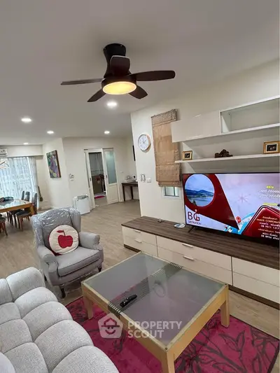Spacious living room with modern decor and ceiling fan, featuring a cozy dining area in the background.