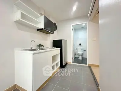 Modern compact kitchen with sleek design and adjacent bathroom in a cozy apartment.