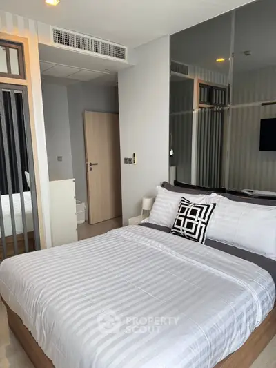 Modern bedroom with stylish decor and mirrored wall in a contemporary apartment.