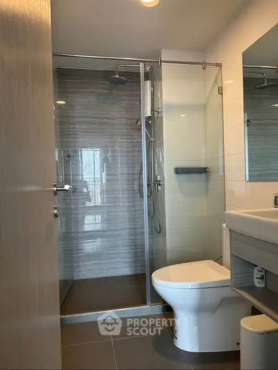 Modern bathroom with glass shower and sleek fixtures in contemporary apartment.