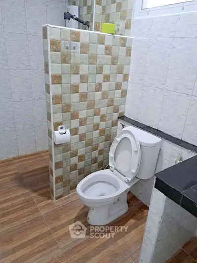 Modern bathroom with stylish tile design and wooden flooring, featuring a sleek toilet and contemporary fixtures.