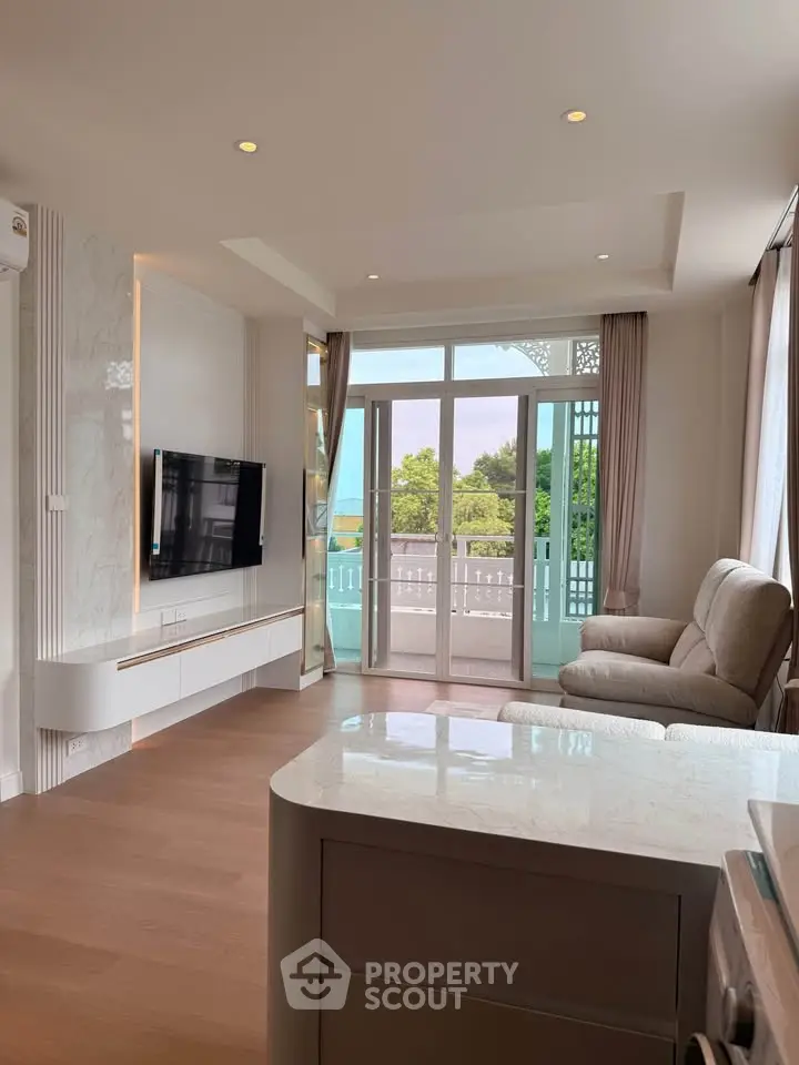 Spacious living room with modern decor and large windows opening to a balcony with a scenic view.