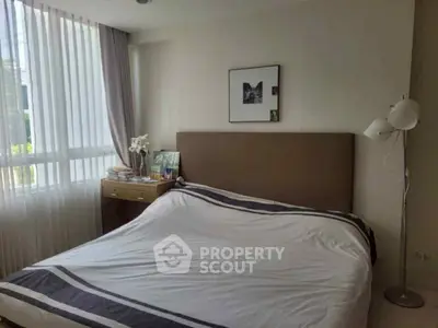 Cozy bedroom with modern decor and natural light from large window.